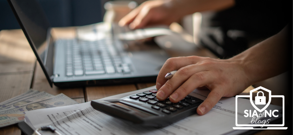 Adobe stock photo for blog titled, "How Much DO You Really Need to Start an Independent Agency". Photo shows a man's hands typing on a laptop, calculator and 100 bills are visible on the table.