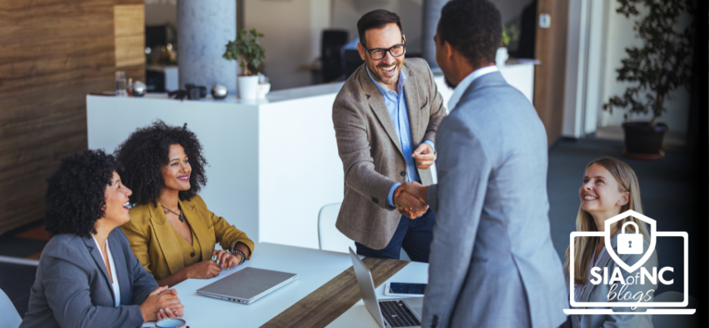 Business professionals meeting in an office, shaking hands to represent agency perpetuation planning and succession transitions.